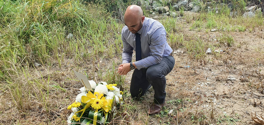 Greg kneeling in long grass, searching the ground