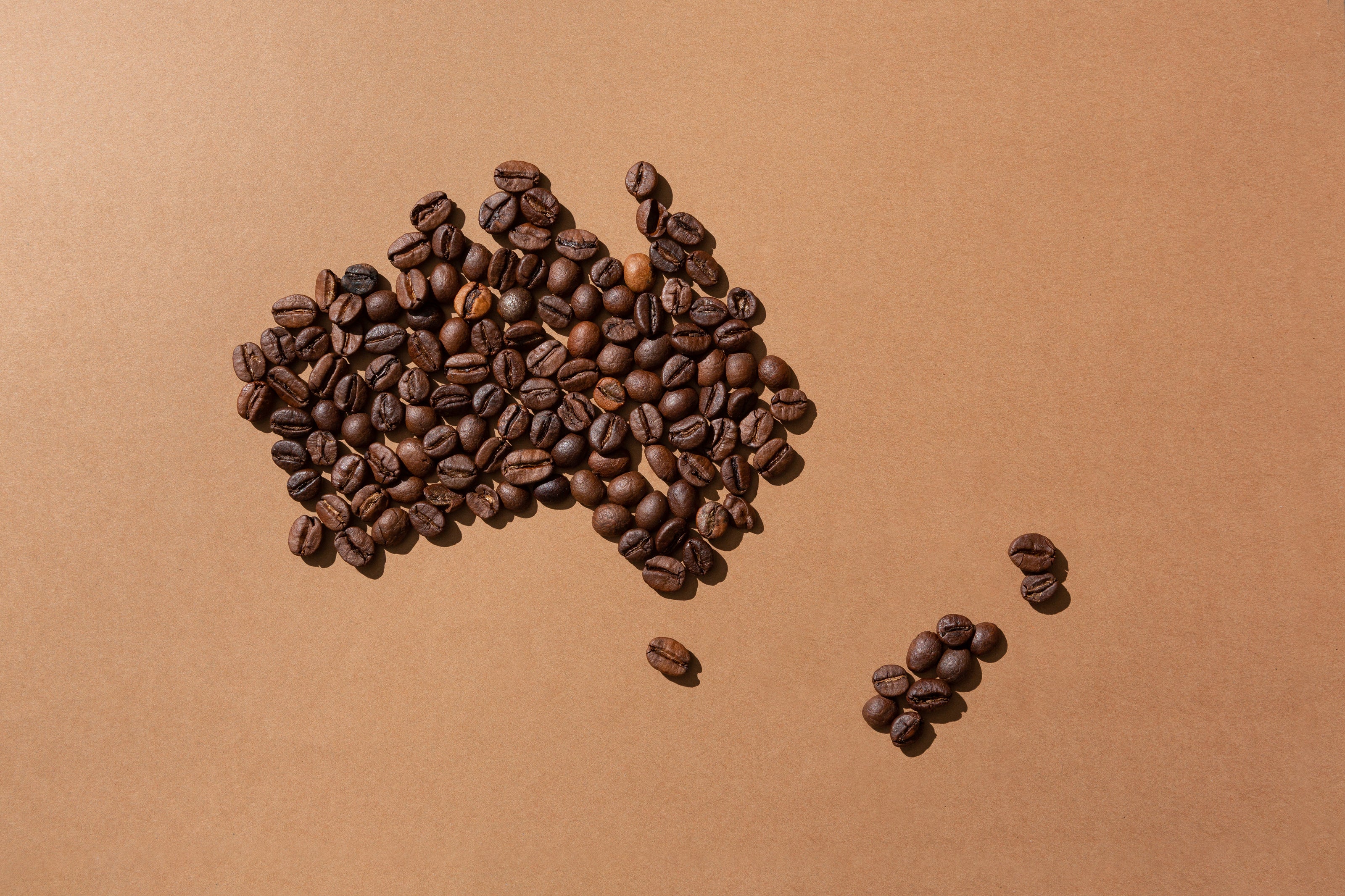 Roasted coffee beans arranged in the shape of Australia on kraft paper